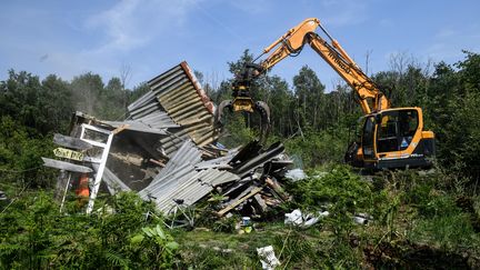 Une pelleteuse&nbsp;détruit une construction dans la Zad de Notre-Dame-des-Landes, le 17 mai 2018, lors de la seconde opération d'évacuations. (FRED TANNEAU / AFP)