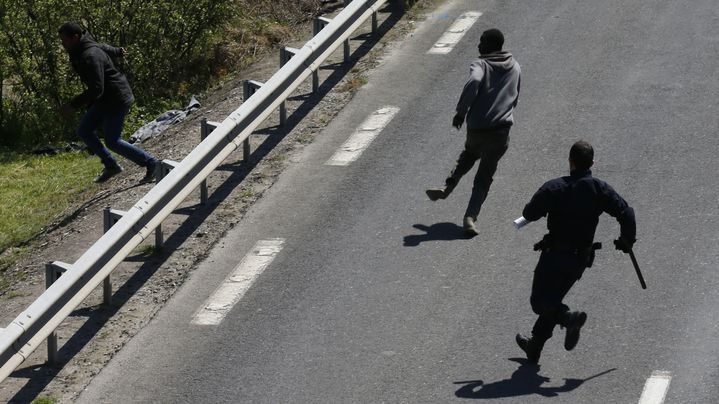 Un policier repousse des migrants aux abords de l'entr&eacute;e du tunnel sous la Manche, le 21 mai 2015, &agrave; Calais. (PASCAL ROSSIGNOL / REUTERS)