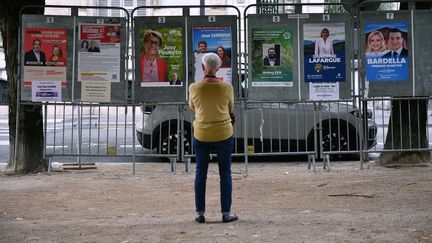 Une femme fait face aux affiches des candidats aux élections législatives à Pau (Pyrénées-Atlantiques), le 30 juin 2024, jour du premier tour. (GAIZKA IROZ / AFP)