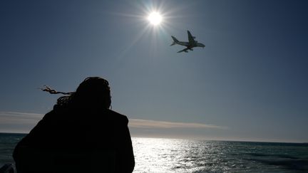 Une promeneuse observe un avion au large de Nice (Alpes-Maritimes), le 29 novembre 2019. (VALERY HACHE / AFP)