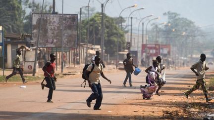 Des habitants de Bangui courent se mettre &agrave; l'abri alors que des tirs retentissent dans la capitale centrafricaine, vendredi 20 d&eacute;cembre 2013.&nbsp; (FRED DUFOUR / AFP)