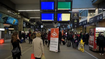 Des passagers devant les panneaux&nbsp;d'affichage de la gare Montparnasse à Paris, le 3 décembre 2017. (MARTIN BUREAU / AFP)