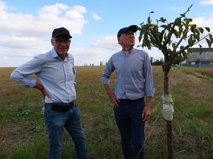 De gauche à droite : Thierry Loyer, membre de l'association, le père Jean-Marie Lioult, initiateur du projet... et le tout premier arbre planté, un prunier !&nbsp; (ISABELLE MORAND / RADIO FRANCE / FRANCE INFO)