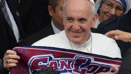 Le pape Fran&ccedil;ois tient une &eacute;charpe de son &eacute;quipe de football favorite, le club argentin de San Lorenzo, le 25 juillet, lors d'une visite &agrave; Rio de Janeiro (Br&eacute;sil). (YASUYOSHI CHIBA / AFP)