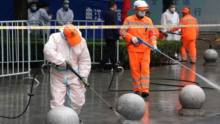 Des agents en tenue de protection intégrale désinfectent les rues à Xi'an,&nbsp;en Chine. (LIU XIAO / XINHUA VIA AFP)