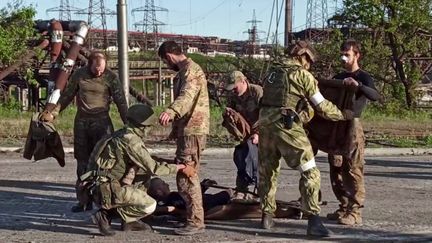 Une capture d'écran d'une vidéo du ministère russe de la Défense montre des soldats ukrainiens être fouillés par des militaires russes alors qu'ils sortent de l'usine Azovstal, le 17 mai 2022. (AFP PHOTO / RUSSIAN DEFENCE MINISTRY / HANDOUT)