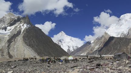 Des porteurs montent des tentes au camping de Concordia devant le sommet du K2 (au centre), dans la chaîne du Karakoram, au nord du Pakistan, le&nbsp;14 août 2019. (AMELIE HERENSTEIN / AFP)