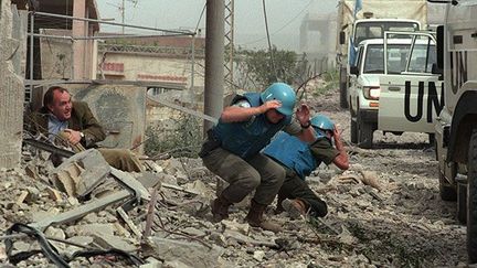 correspondant de l'AFP, et des membres de la Force de l’ONU au Liban, chargés d’évacuer les habitants du village d'al-Mansouri près de Tyr, au Liban sud, lors d’un violent bombardement israélien, le 15 avril 1996. 

En 1996, le Liban sud subit des affrontements entre le Hezbollah, mouvement politique chiite libanais, et les Israéliens, qui occupent alors cette région. 

Pour y remédier et détruire les positions du Hezbollah, l’armée israélienne lancera une série de bombardements entre le 11 et le 27 avril. (AFP/RAMZI HAIDAR )