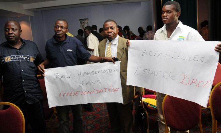 Démonstration d'anciens employés de la Comuf, au Gabon, en 2010 lors d'une assemblée générale de l'Observatoire de la santé de Mounana (OSM). On peut lire sur l'une des banderolles: «Pas d'observatoire sans indemnisation». (WILS YANICK MANIENGUI / AFP)