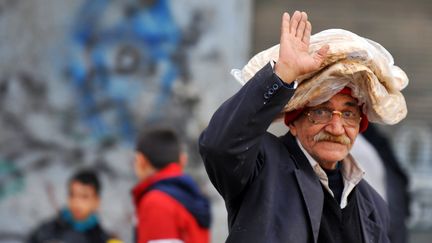 Un vieil homme salue le photographe apr&egrave;s &ecirc;tre all&eacute; chercher du pain, le 14 f&eacute;vrier 2013 &agrave; Alep (Syrie).&nbsp; (BULENT KILIC / AFP)