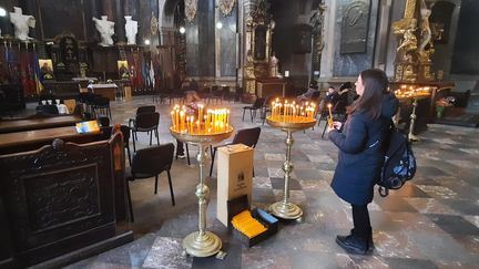 Une personne allume une bougie dans l'église des&nbsp;Saints-Apôtres-Pierre-et-Paul de Lviv (Ukraine), mardi 15 mars 2022. (SANDRINE ETOA-ANDEGUE)