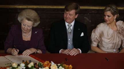 La reine Beatrix, aux c&ocirc;t&eacute;s du prince Willem-Alexander et de son &eacute;pouse Maxima,&nbsp;signe l'acte d'abdication, le 30 avril 2013, au palais royal d'Amsterdam (Pays-Bas). (BART MAAT / AFP)