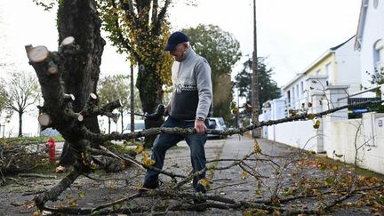 Un habitant de Saint-Nazaire (Loire-Atlantique) découpe une branche d'arbre tombée après le passage de la tempête Ciaran, dans la nuit du 1er au 2 novembre 2023. (SEBASTIEN SALOM-GOMIS / AFP)