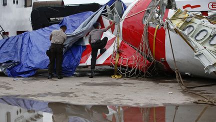 Des policiers indon&eacute;siens inspectent une partie de l'avion d'AirAsia, qui s'&eacute;tait ab&icirc;m&eacute; en mer le 28 d&eacute;cembre 2014. (DARREN WHITESIDE / REUTERS)