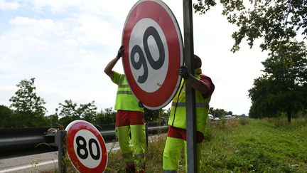 Des employés de la&nbsp;Direction interdépartementale des routes de l'Est remplacent des panneaux de limitation de vitesse à 90 km/h par des 80 km/h (illustration). (SEBASTIEN BOZON / AFP)