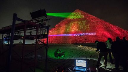 "Merci à ceux qui veillent sur notre sécurité", "Restez chez vous, restez en sécurité" figurent parmi les messages projetés par des faisceaux lumineux sur la pyramide de Kheops pour inciter les Egyptiens à rester confinés.&nbsp; &nbsp; (KHALED DESOUKI / AFP)