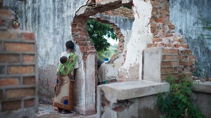 son enfant attaché dans le dos, dans les ruines d’une maison coloniale aux abords du site de déplacés internes de Katanika. A Kalemie, les femmes célibataires et les veuves qui n’ont pas accès à un abri approprié courent un risque élevé d’abus et de violences sexuelles.
 
 (Colin Delfosse/UNHCR       )