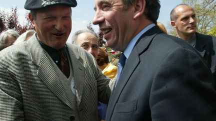 Un homme coiffé d'un béret basque serre la main de François Bayrou alors candidat UDF pour la présidentielle, à Bordères, le 19 avril 2002. (MICHEL GANGNE / AFP)