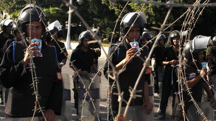 Pause jus de pommes pour des policiers anti-&eacute;meutes lors d'une manifestation d'opposants devant le palais pr&eacute;sidentiel au Caire (Egypte), le 24 ao&ucirc;t 2012. (ASMAA WAGUIH / REUTERS)