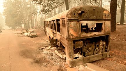 Après le passage des flammes, les photographes découvrent un car de ramassage scolaire calciné au bord d'une route de Paradise (Californie), le 9 novembre 2018. (JOSH EDELSON / AFP)