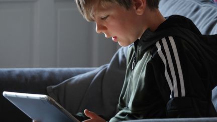 Un enfant regarde sa tablette. (MATT CARDY / GETTY IMAGES EUROPE)