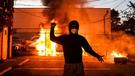 Un jeune manifestant derrière une voiture qui brûle à Minneapolis, le 29 mai 2020.&nbsp; (CHANDAN KHANNA / AFP)