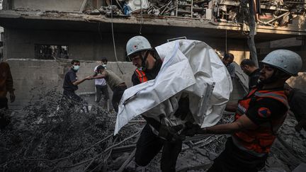 Des membres de la protection civile et des résidents évacuent les habitants d'un immeuble bombardé par l'armée israélienne, dans la ville de Khan Younès dans la bande de Gaza, le 14 octobre 2023. (MUSTAFA HASSONA / ANADOLU / AFP)