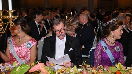 Le prix Nobel de physique, Alain Aspect, entouré de la famille royale suèdoise, la princesse Victoria à sa gauche et  la Reine Silvia à sa droite, lors de la cérémonie de remise du prix Nobel le 10 décembre 2022 à Stockholm (JONATHAN NACKSTRAND / AFP)