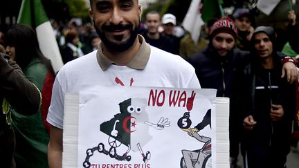 Un homme tient une pancarte, le 8 mars 2019 à Alger, à l'adresse du président Abdelaziz Bouteflika : "Tu rentres plus dans le cadre." (RYAD KRAMDI / AFP)