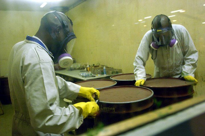 Des travailleurs sud africains vérifient des fûts contenant des déchets nucléaires avant de les stocker. (Photo AFP/Guercia Gianluigi)