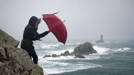 Une femme lutte contre le vent lors d'une tempête, à la pointe du Raz (Finistère), le 21 décembre 2015. (GARCIA JULIEN / HEMIS.FR / HEMIS.FR)