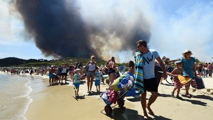 Des personnes quittent la plage de Bormes-les-Mimosas (Var) alors que feu fait rage derrière eux, le 26 juillet 2017.&nbsp; (ANNE-CHRISTINE POUJOULAT / AFP)