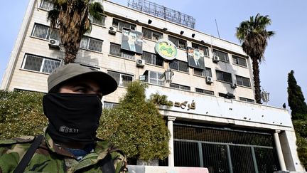 Un rebelle syrien devant le siège du parti Baas à Damas, le 12 décembre 2024 (LOUAI BESHARA / AFP)