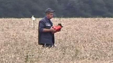 Un secouriste porte un bo&icirc;tier pouvant &ecirc;tre l'une des bo&icirc;tes noires de l'avion de Malaysia Airlines,&nbsp;le 18 juillet 2014, &agrave; Hrabove (est de l'Ukraine). (REUTERS TV / REUTERS )