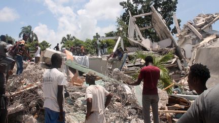 Des habitants des Cayes recherchent des blessés au milieu des décombres, samedi 14 août 2021, après le séisme qui a frappé Haïti dans la matinée. (STANLEY LOUIS / AFP)