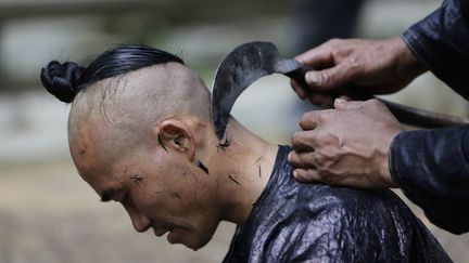 Un homme de l'ethnie Miao se fait raser la t&ecirc;te &agrave; Basha (Chine), le 22 mai 2013. (JASON LEE / REUTERS)