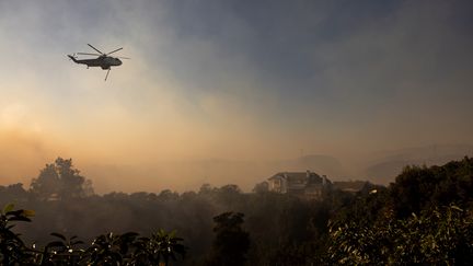 Un hélicoptère survole un vaste incendie, à Moorpark, en Californie (Etats-Unis), le 7 novembre 2024. (ETIENNE LAURENT / AFP)