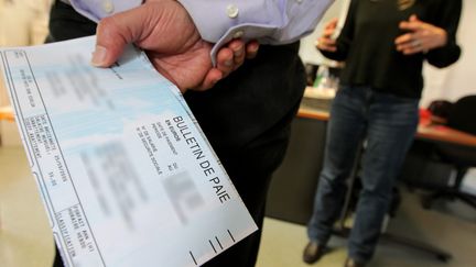 Un homme tient un bulletin de paie à la main. (FRANÇOIS DESTOC / MAXPPP)