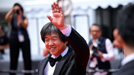 Le réalisateur chinois Wang Bing salue sur le tapis rouge. Ce cinéaste engagé, qui s'emploie à donner une voix aux laissés pour compte de son pays, présente avec "Jeunesse (Le Printemps)" le film le plus long projeté au festival cette année (3h30). Mais il présente également en séance spéciale "Man in Black", sur un compositeur de musique classique chinois persécuté, Wang Xilin, long de seulement 60 minutes. (STEPHANE CARDINALE - CORBIS / CORBIS ENTERTAINMENT / GETTY)