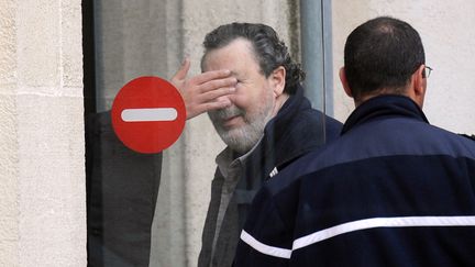 Philippe Berre (C), dont le visage est camouflé par la main de son avocat, devant le tribunal correctionnel de La Rochelle (Charente-Maritime), le 5 avril 2012. (XAVIER LEOTY / AFP)