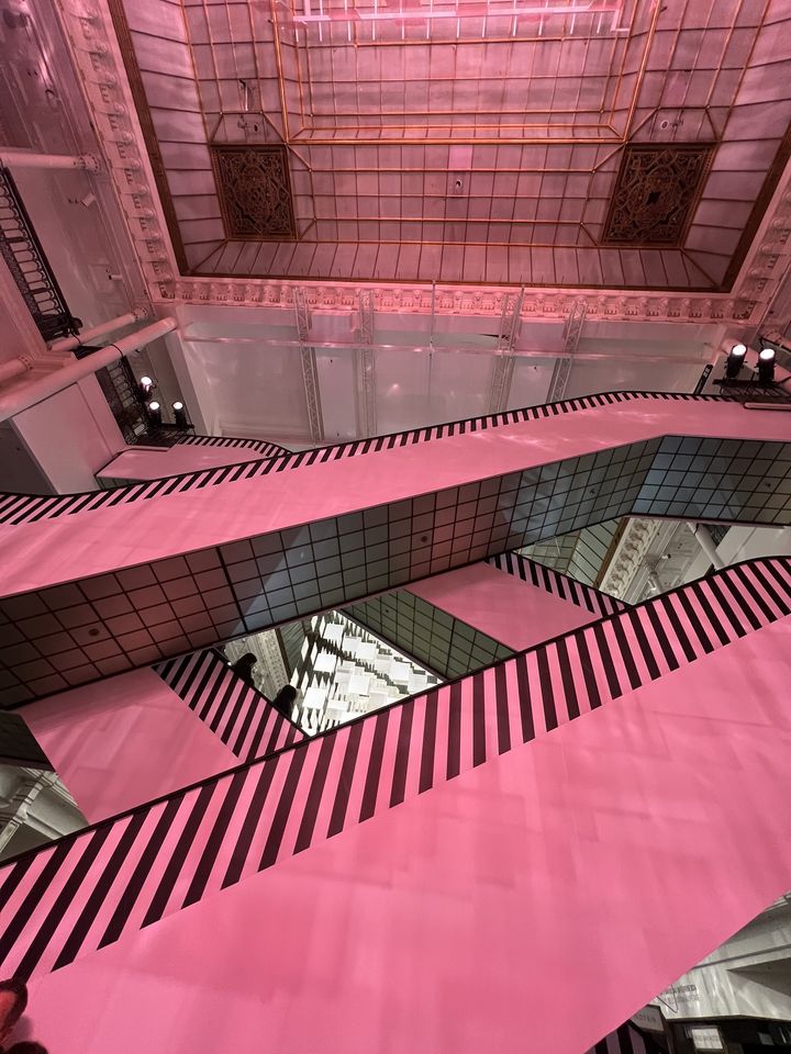 Carte blanche de Daniel Buren au Bon Marché Rive Gauche pour l'exposition  "Aux Beaux Carrés, travaux in situ" : depuis le rez-de-chaussée, l'escalator qui mène aux étages. Janvier 2024. (OLESYA OKUNEVA)