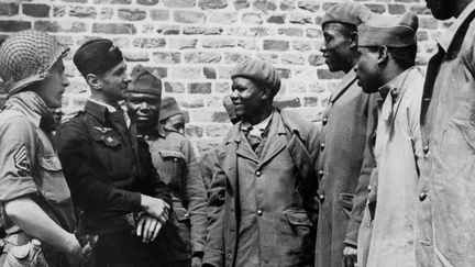 Fin juillet 1944 en Normandie : des soldats francais&nbsp;venus d'Afrique, capturés par les Allemands en 1940 et qui viennent d'être libérés de leur "Frontstalag", discutent avec un soldat de la VIIe US Army et un officier aviateur francais. (USIS / AFP)