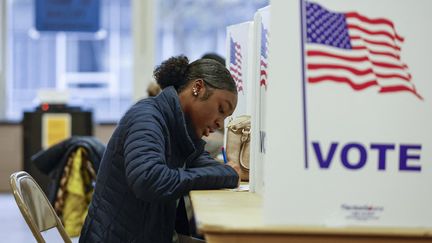 Une femme remplit son bulletin de vote anticipé, à Ottawa, dans l'Etat du Michigan. (KAMIL KRZACZYNSKI / AFP)