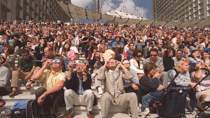 Des Français observent l'éclipse totale de soleil du 11 août 1999 sur le parvis de La Défense, à Paris.. (MAXPPP)