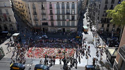 Vue aérienne des fleurs et des bougies disposées, le 22 août 2017, sur une place de Barcelone en mémoire des victimes des attentats qui ont fait 15 morts en Catalogne. (LLUIS GENE / AFP)