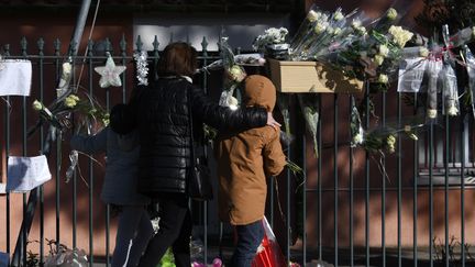 Une femme et un enfant devant la mairie de&nbsp;Saint-Féliu-d'Avall (Pyréenées-Orientales), le 17 décembre 2017, où un rassemblement en l'hommage des victimes de la collision entre un TER et un bus scolaire a eu lieu.&nbsp; (PASCAL PAVANI / AFP)