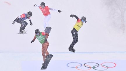 Dossard rouge, Chloé Trespeuch assiste impuissante à la victoire des Américains en quart de finale de snowboard cross aux JO de Pékin, le 12 février 2022. (MARCO BERTORELLO / AFP)