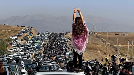 Cette photo d'une femme non voilée devant des milliers de personnes qui se dirigeaient vers le cimetière de la ville natale de Mahsa Amani a fait le tour du monde, le 26 octobre 2022. (UGC / AFP)