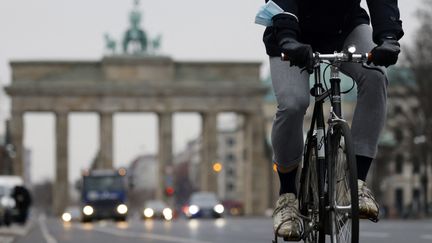 Un cycliste pédale sur la piste cyclable près de l'emblématique porte de Brandenburger, dans le centre de Berlin (Allemagne), le 7 décembre 2020. (ODD ANDERSEN / AFP)