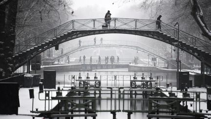 Des passants traversent le canal Saint-Martin, à Paris. (ALAIN JOCARD / AFP)